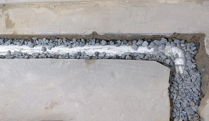 top view of an unfinished french drain partially covered with drainage rocks